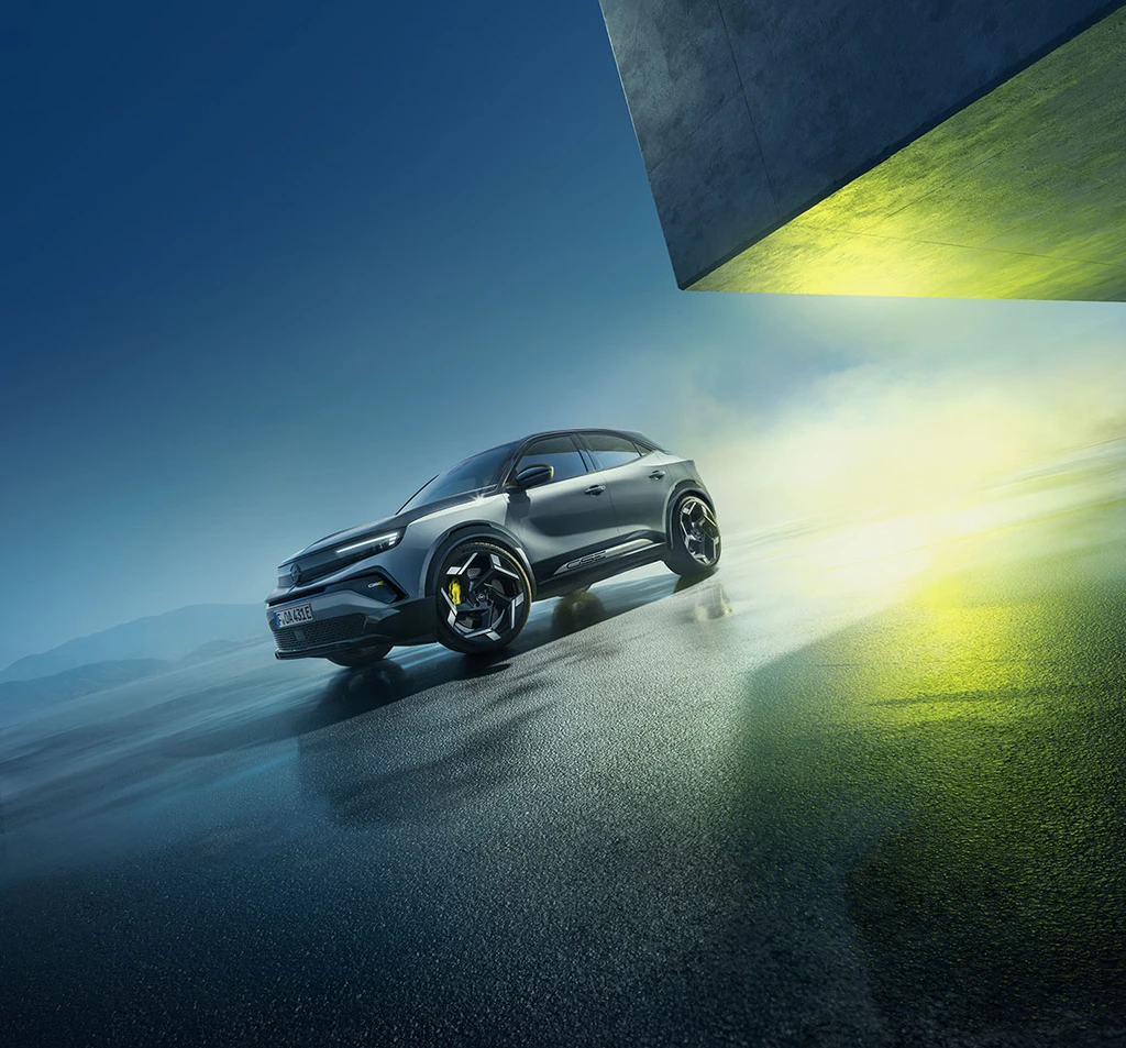 Der neue Mokka GSE, ein kompakter SUV mit sportlichem Design, auf nassem Asphalt vor einem modern beleuchteten Gebäude.